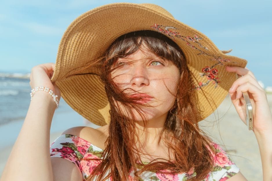 Femme portant un chapeau de paille au bord de la mer pour protéger son cuir chevelu du soleil